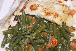 Рыба с зеленой фасолью в пергаменте на сковороде.